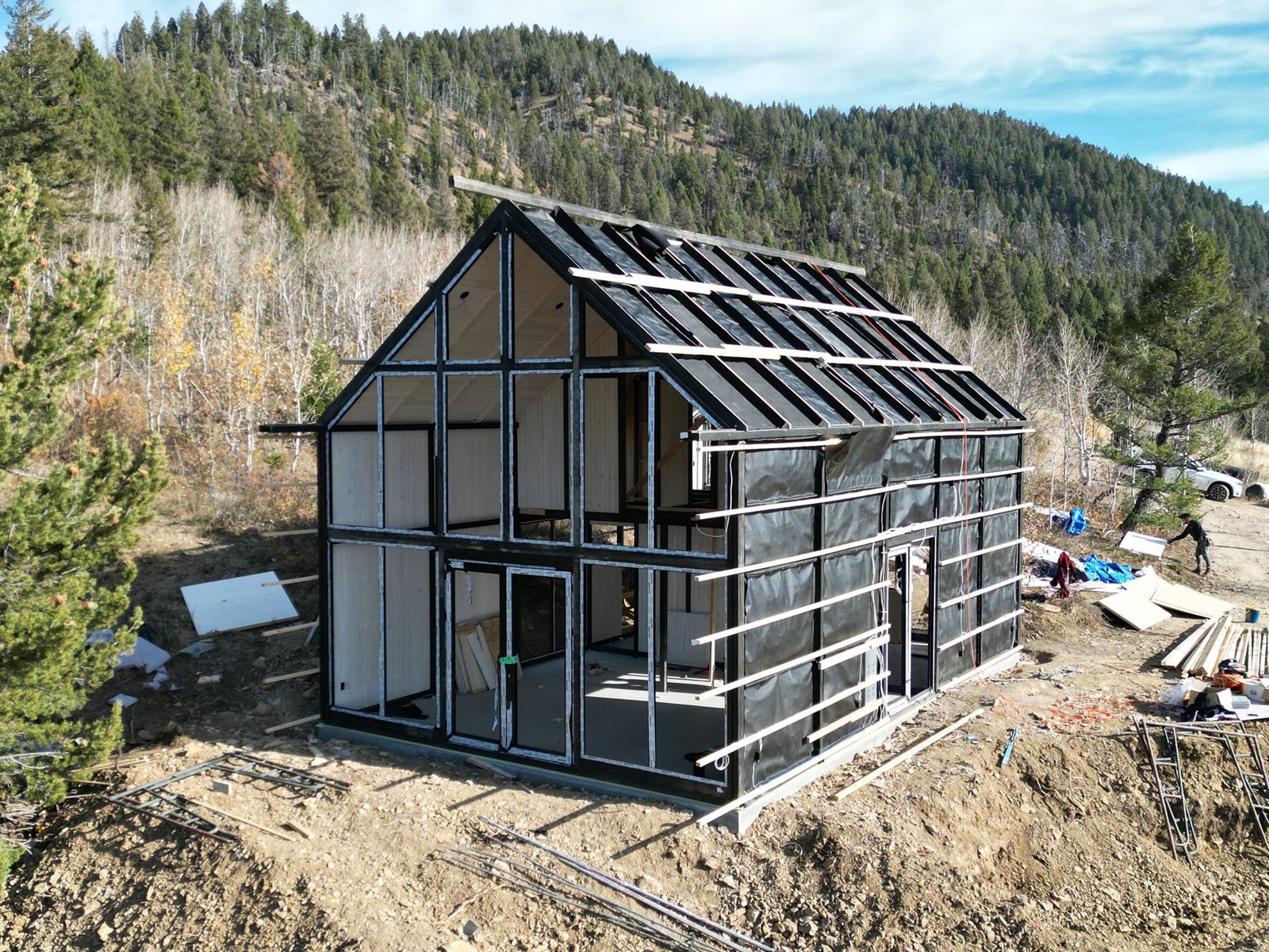 Aerial three-quarter view of an Aries 116 cabin with exposed roof framing during construction in Island Park, ID.