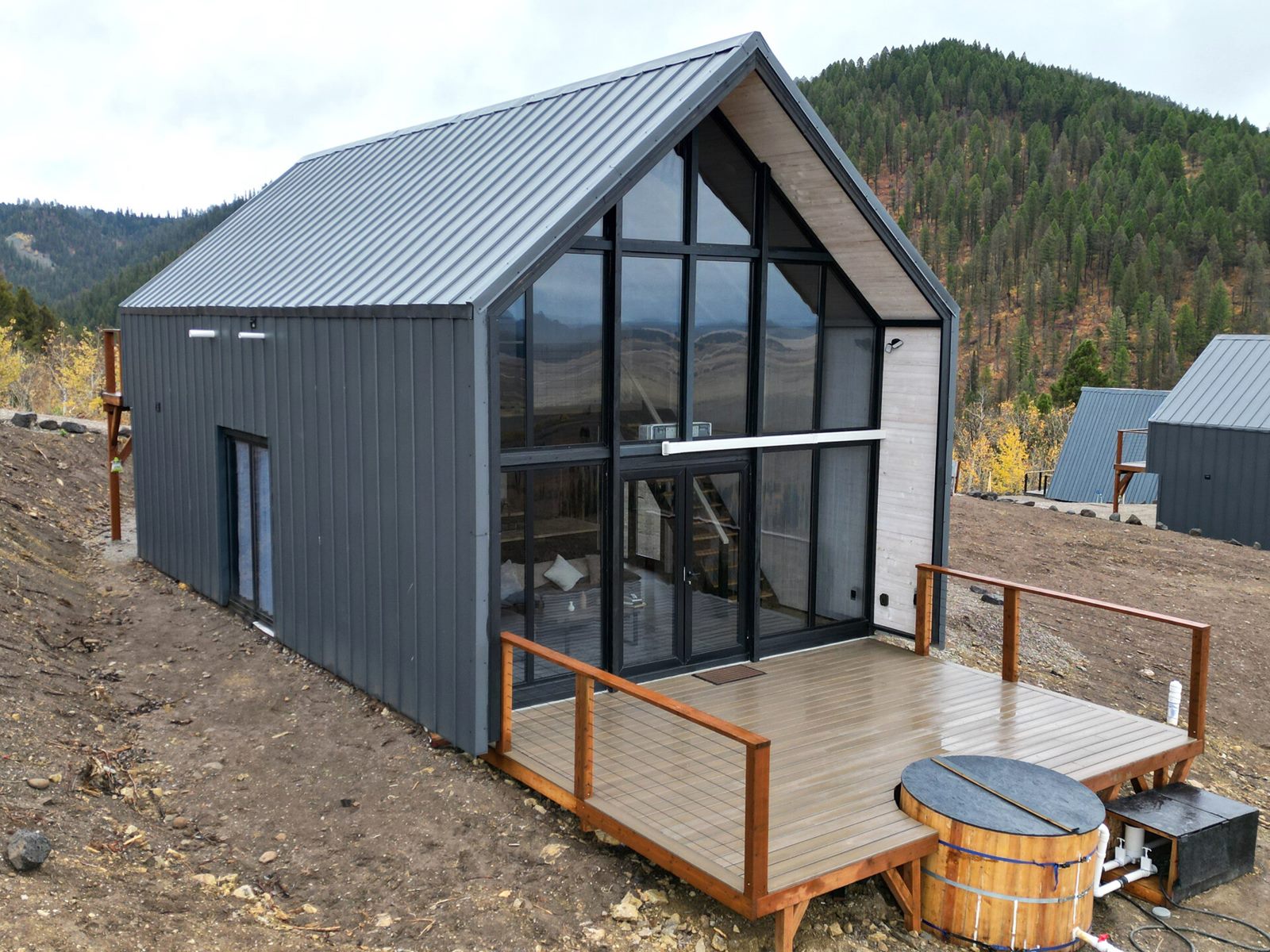 Aerial three-quarter view of an Aries 116 cabin with glass facade and locally built deck in Island Park, ID.