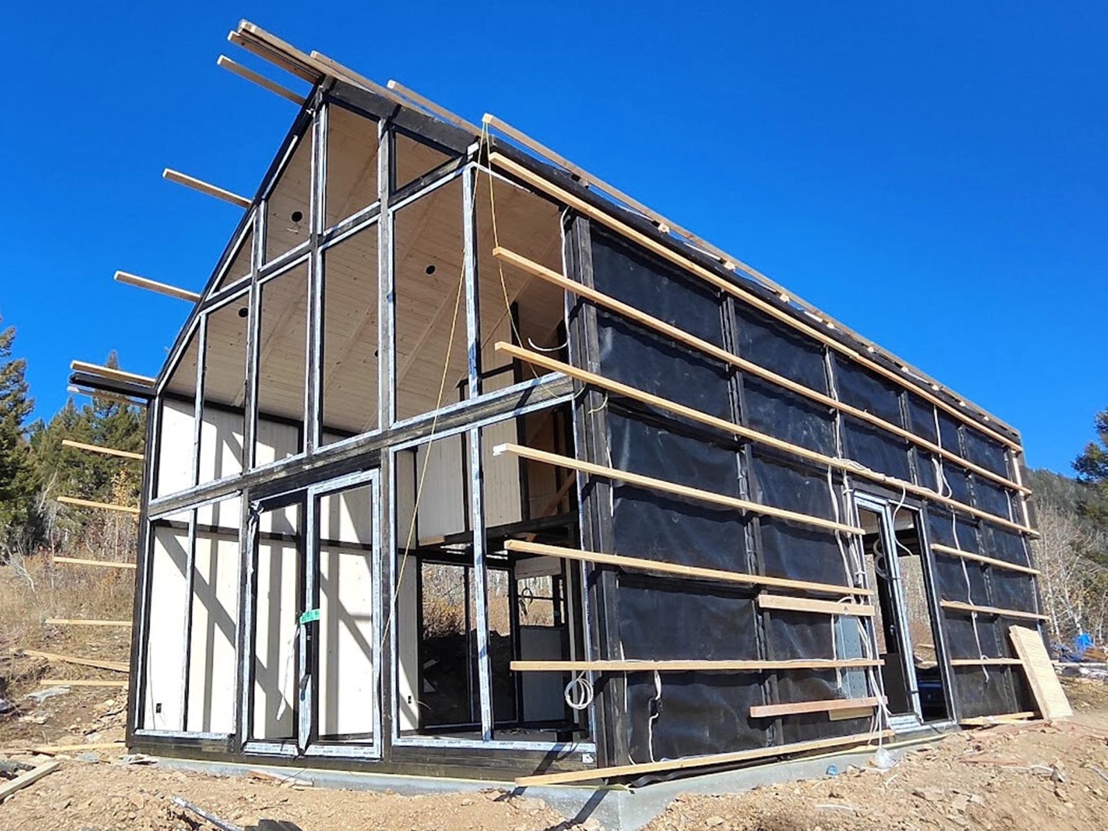 Unfinished Aries 116 cabin with roof and exterior wall framing in Island Park, ID.