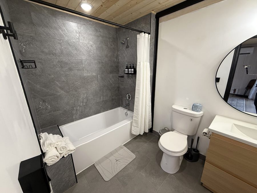 Wide view of a bathroom with bathtub, toilet and vanity inside an Aries 116 cabin in Island Park, ID.