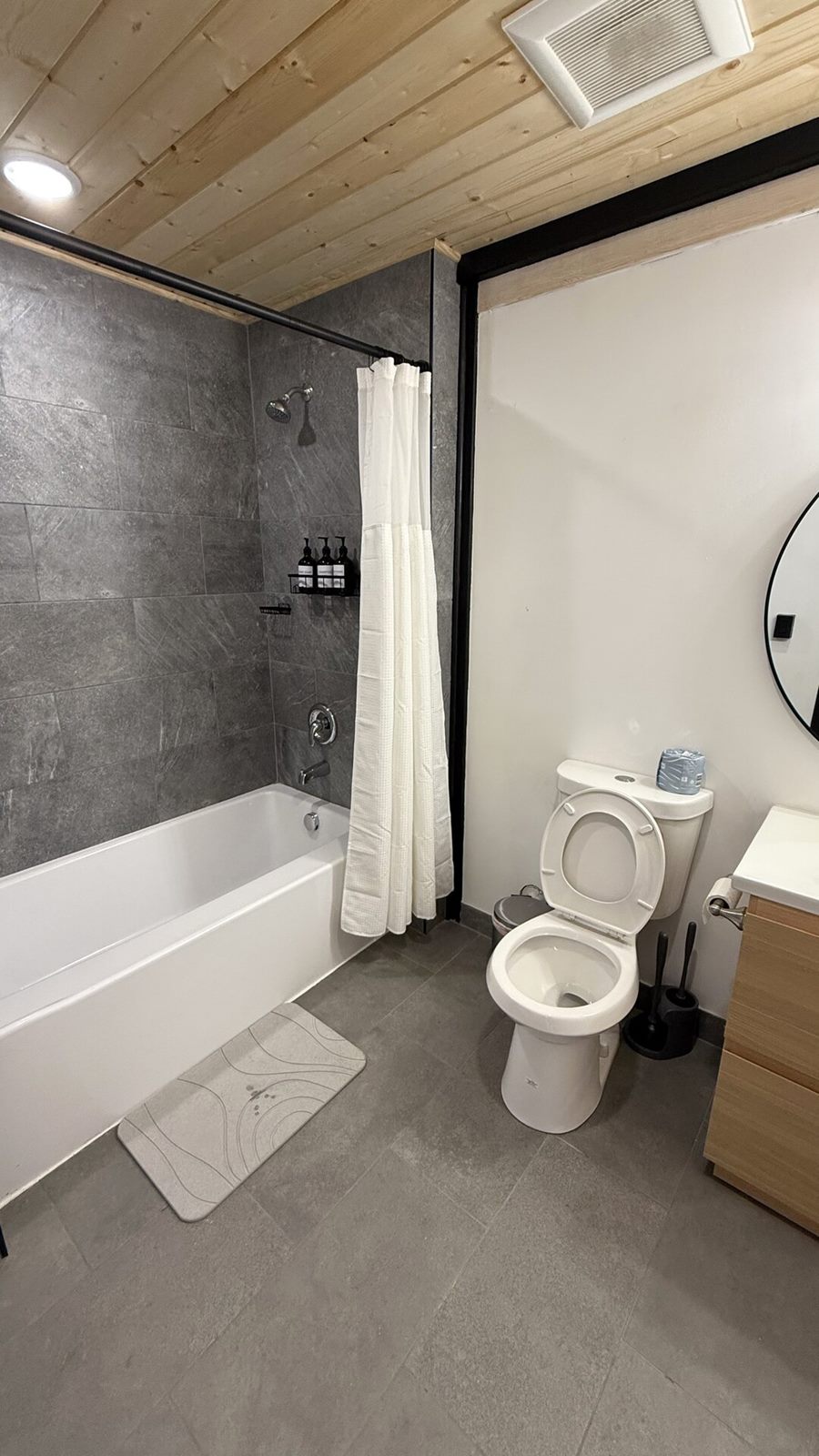 Vertical view of a bathroom with bathtub, toilet and vanity inside an Aries 116 cabin in Island Park, ID.