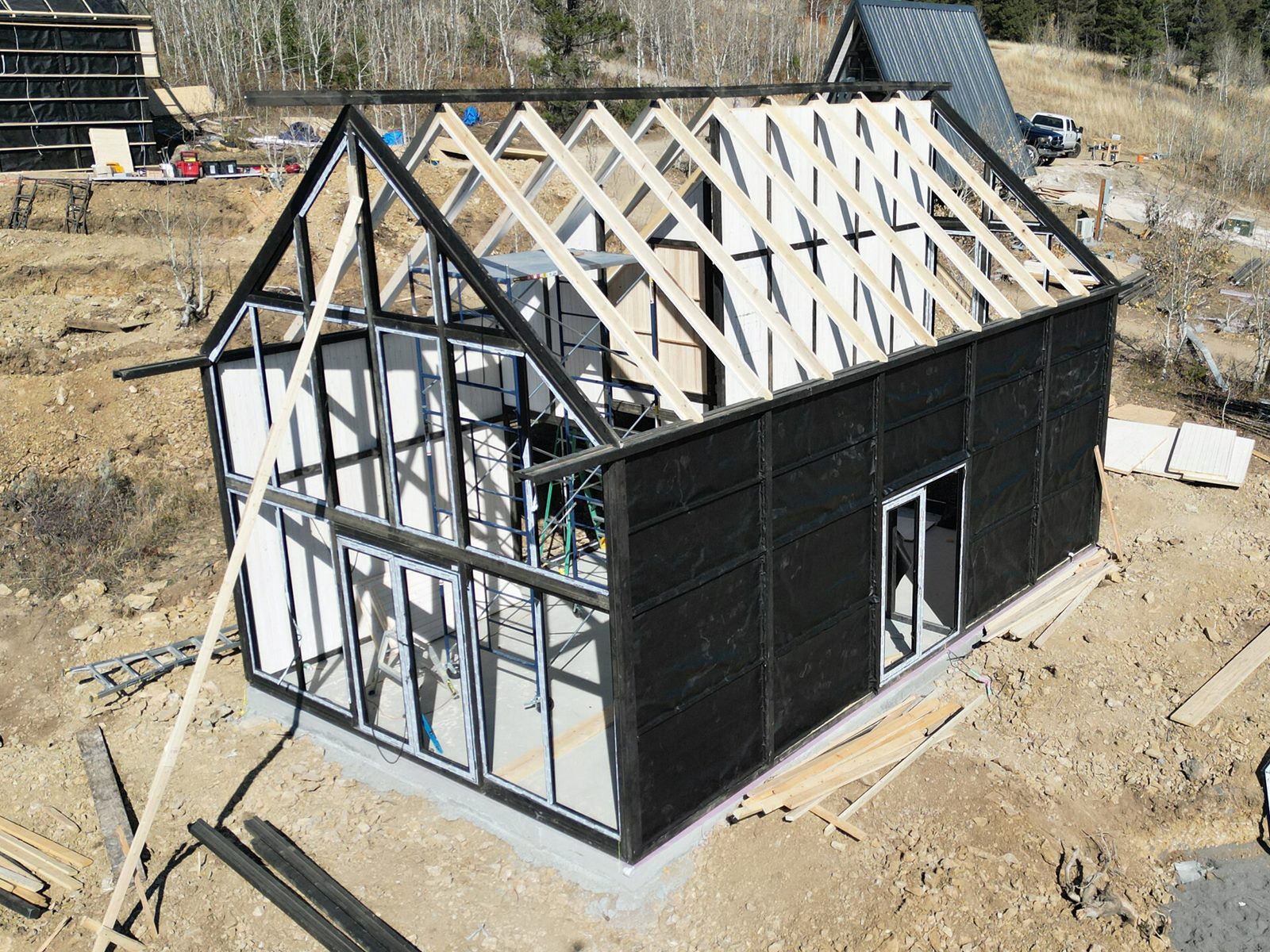 Aerial three-quarter view of an Aries 116 cabin with exposed roof trusses in Island Park, ID.
