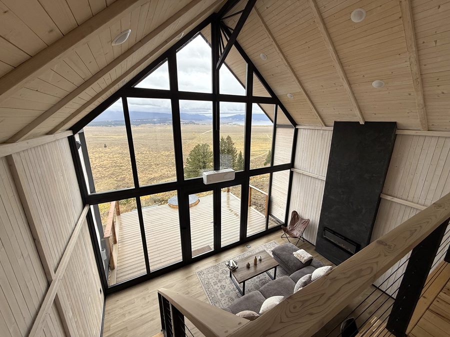 View from the loft over the living area, front windows and fireplace inside an Aries 116 cabin in Island Park, ID.