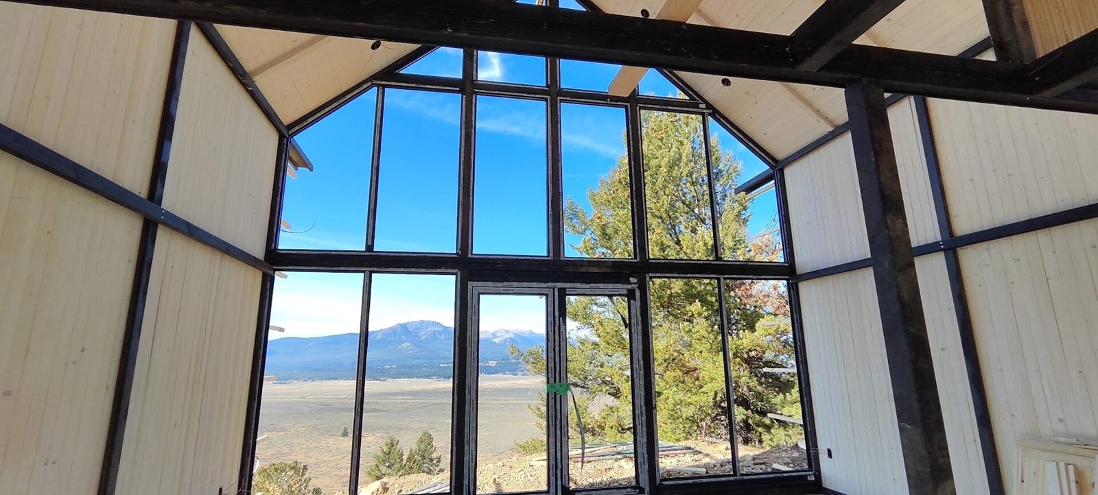 Interior view of the tall front window wall of an Aries 116 cabin during construction in Island Park, ID.