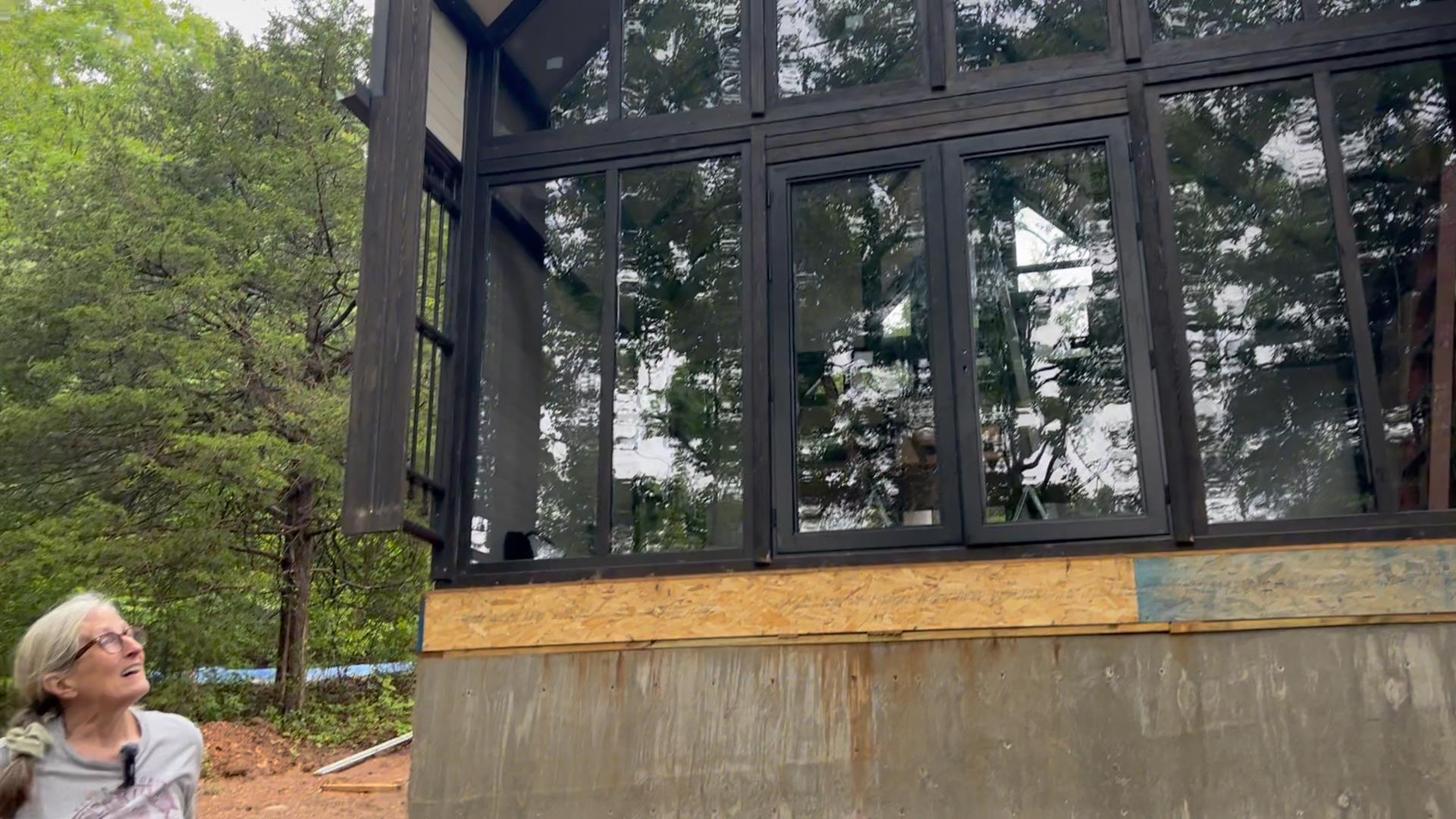 Customer testimonial moment in front of the Aries 96 modern A-frame cabin glass facade during the Arkansas project.
