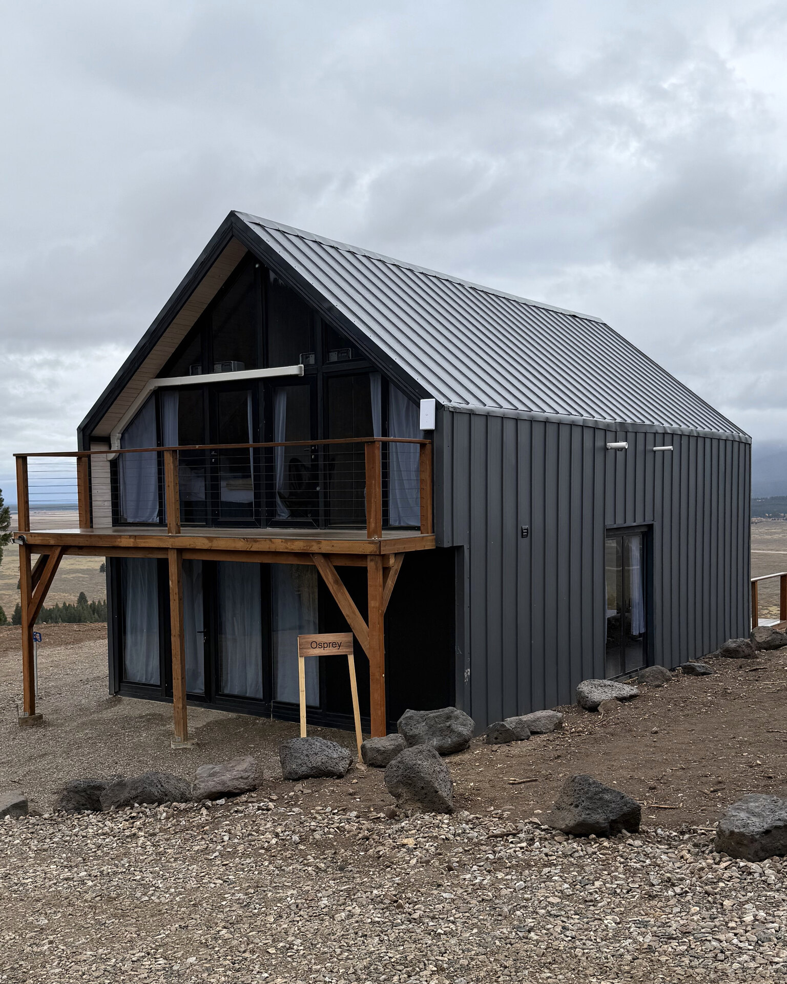 Completed Aries 116 cabin with dark metal cladding and an upper wooden balcony in Island Park, Idaho.