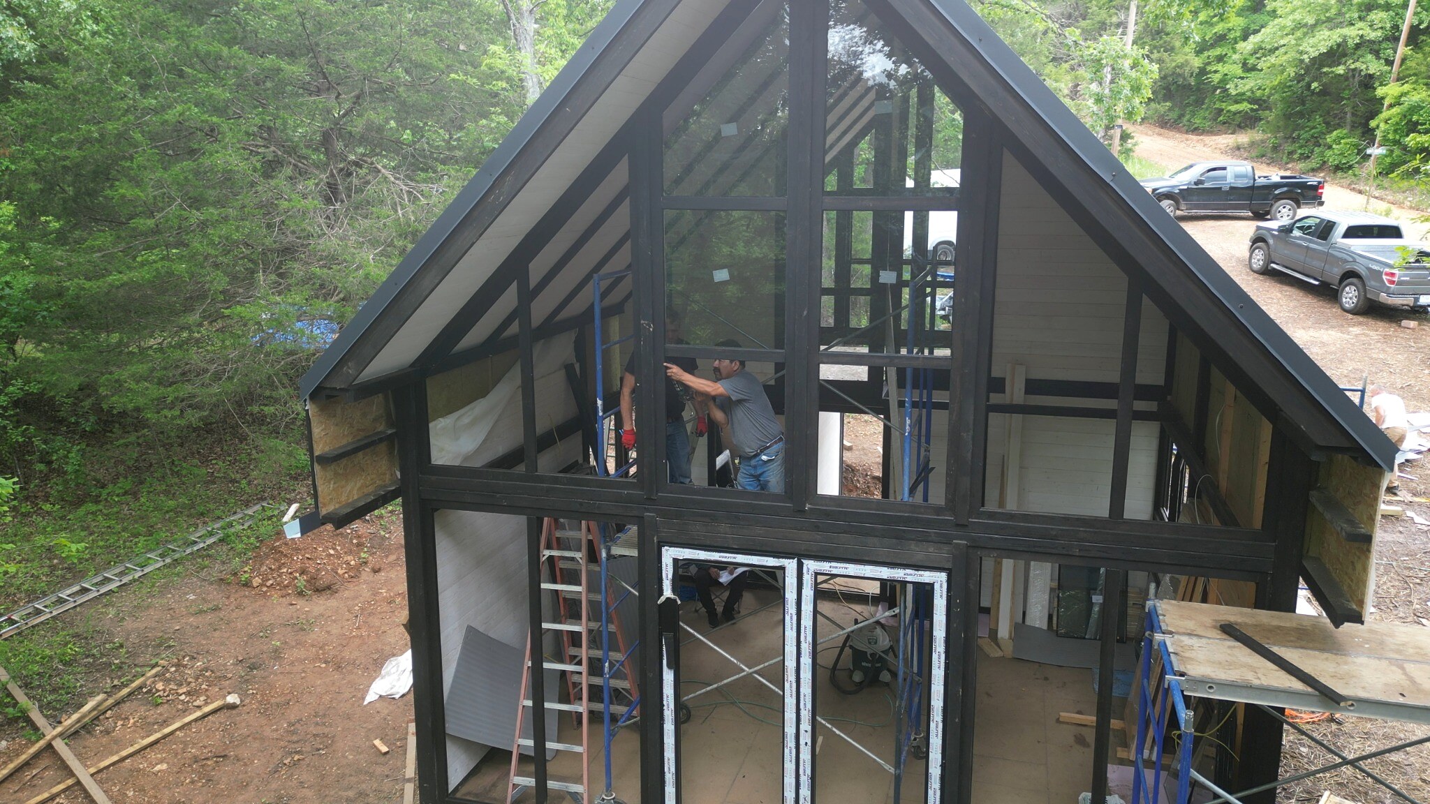 Panoramic glazing installation during the Aries 96 modern cabin build in Arkansas.