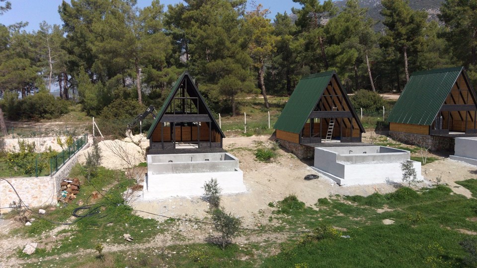 Earlier Stella 70 resort cabins under construction beside unfinished pool shells
