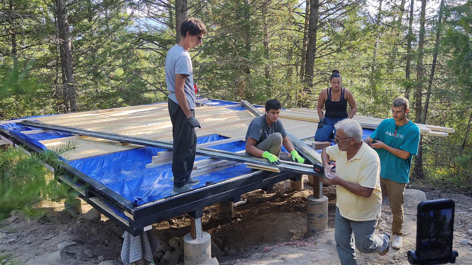 Local crew assembling the Stella 53 A-frame cabin kit on a prefabricated crawl-space foundation in Montana.