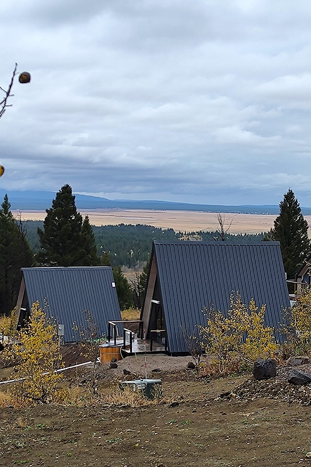 Multiple completed Stella 53 A-frame cabins across the wooded Island Park, ID hospitality site.