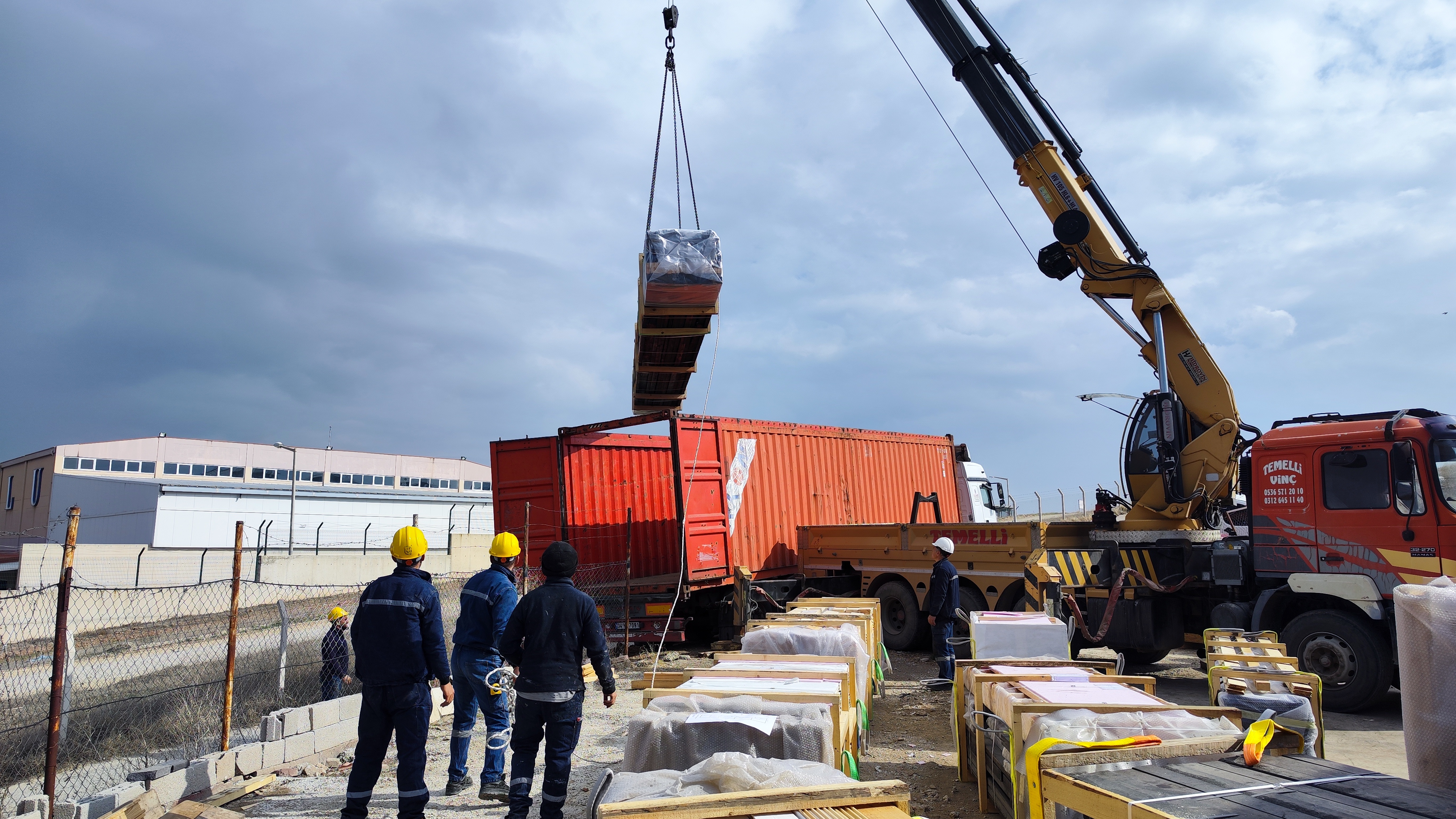 Crane loading the Aries 96 cabin-kit shipment into an open-top container.