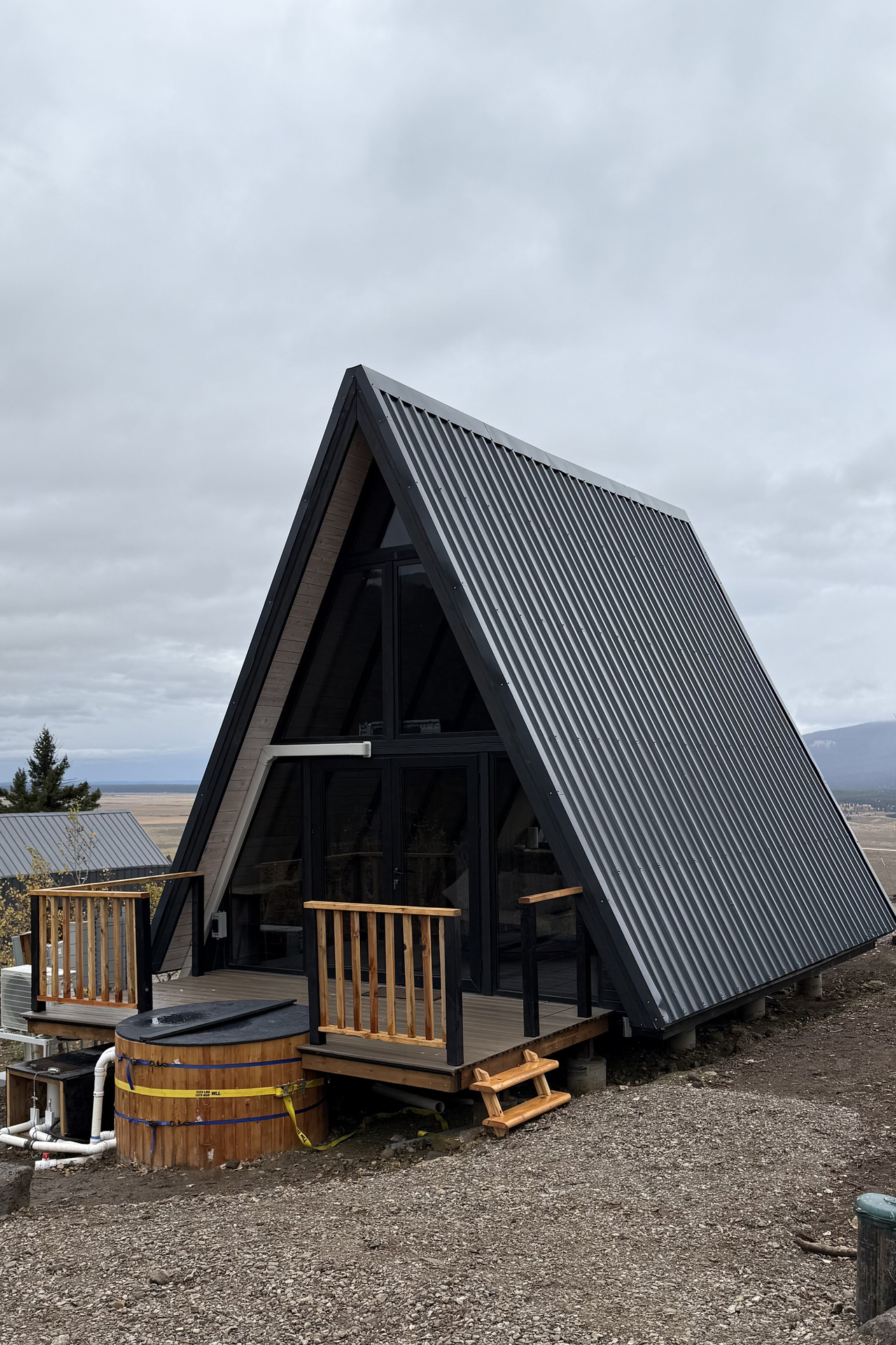 Rear three-quarter view of a completed Stella 53 cabin with deck and hot tub in Island Park, Idaho.