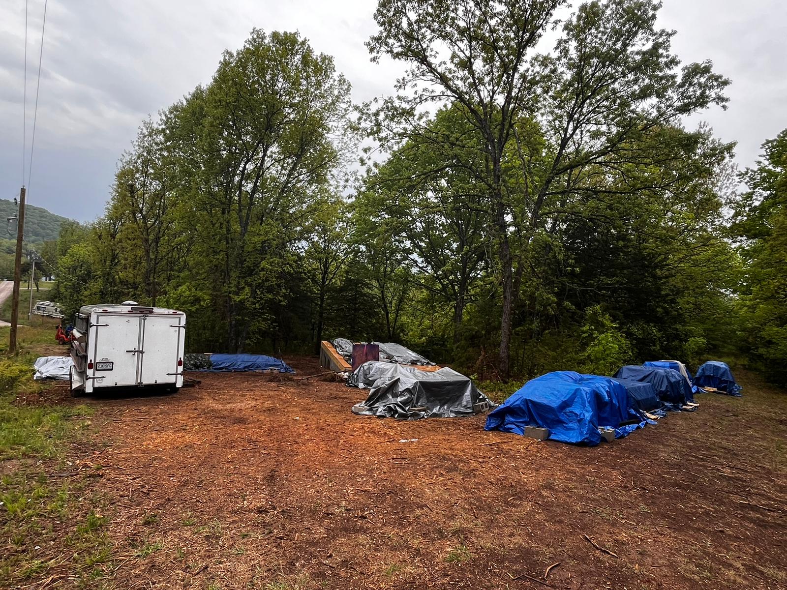 Aries 96 cabin-kit materials protected and stored on the wooded Arkansas site.