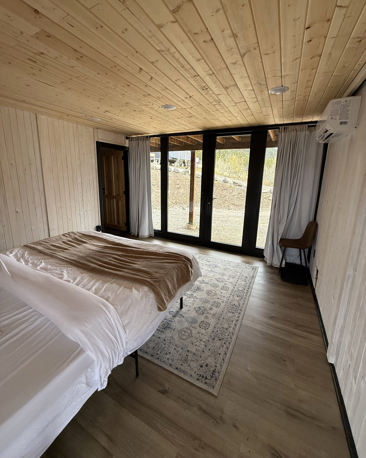 Bedroom with a bed facing glass doors inside an Aries 116 cabin.
