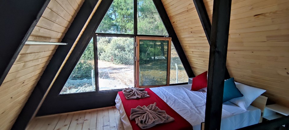 Loft bed beneath the full-height A-frame window. Earlier Stella 70 application; project finishes and amenities vary.