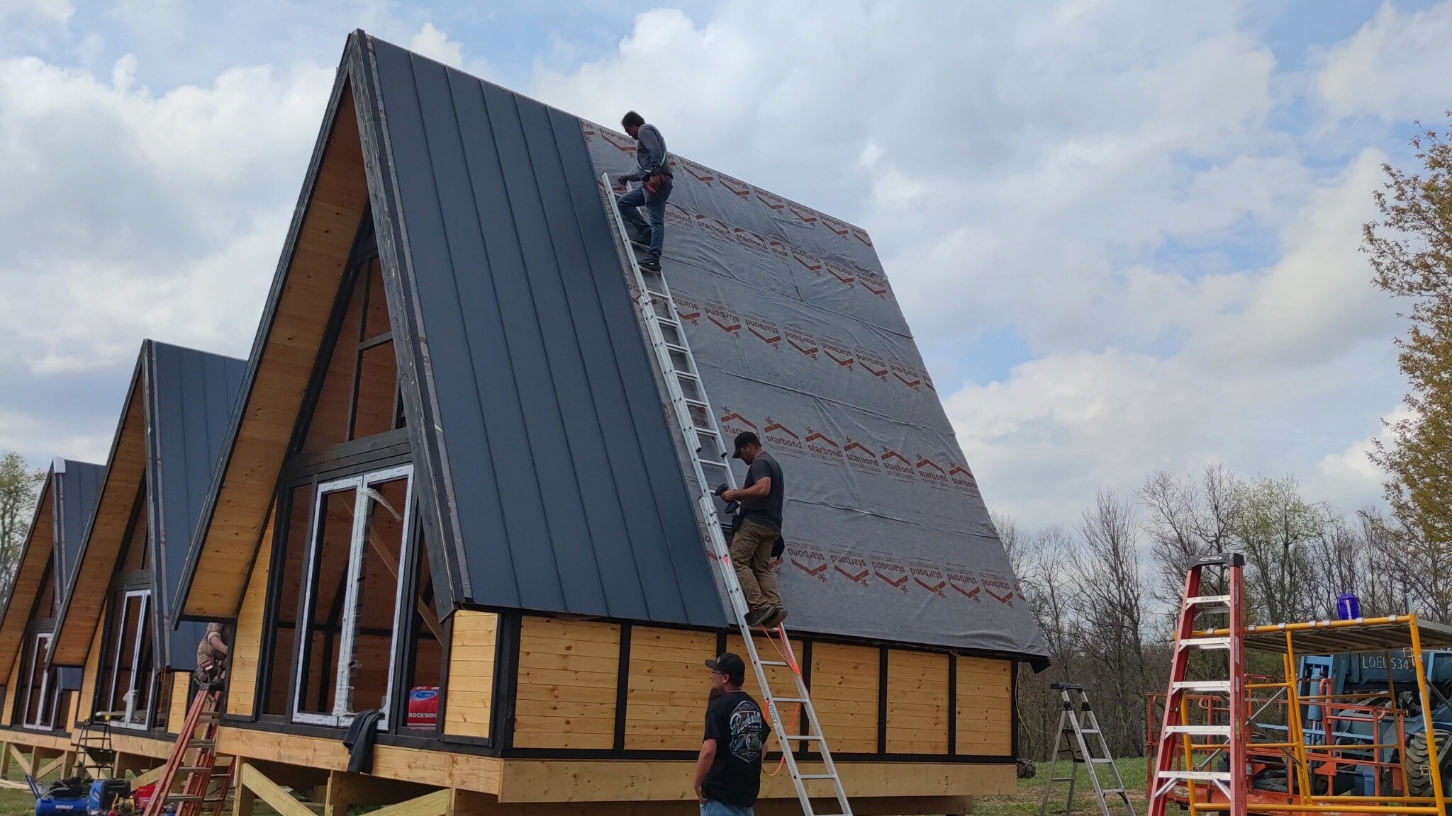 Standing-seam metal roofing panels being installed on a Stella 70 cabin at WV ATV Resort