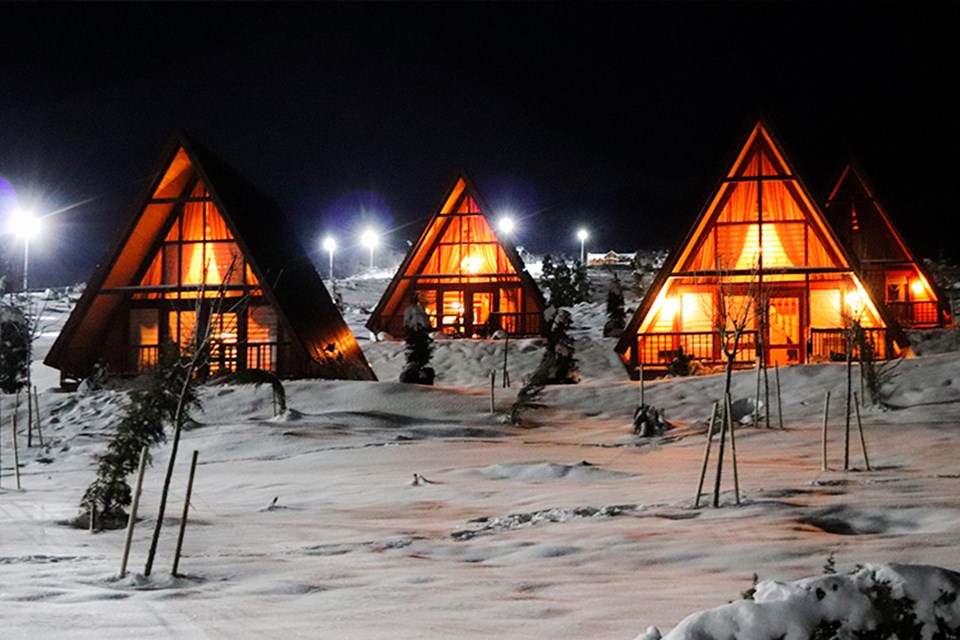 Completed cabins in the snow at night.