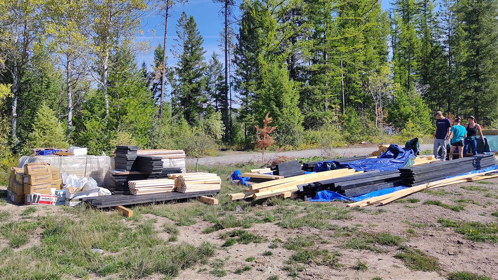 Montana cabin kit site preparation with materials staged on a remote wooded property