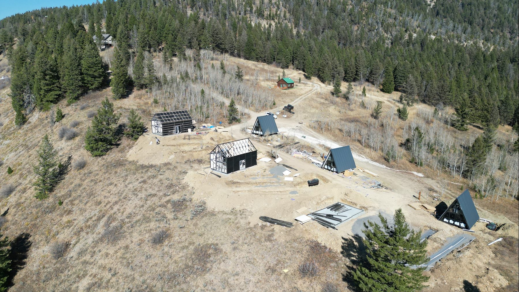 Aerial view of Aries 116 cabins under construction and Stella 53 cabins across the sloped Island Park, ID rental site.