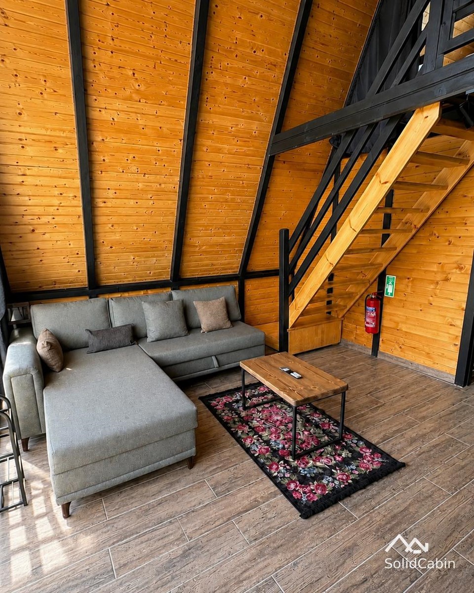 A completed project interior with timber lining, a sofa and the loft staircase.