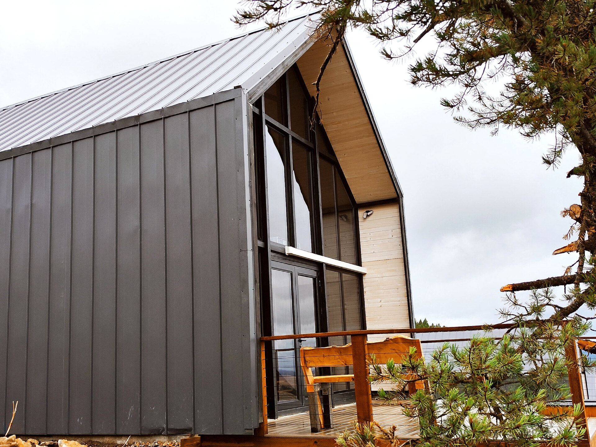 Side elevation of an Aries 116 cabin with dark vertical metal cladding and front glazing in Island Park, Idaho.