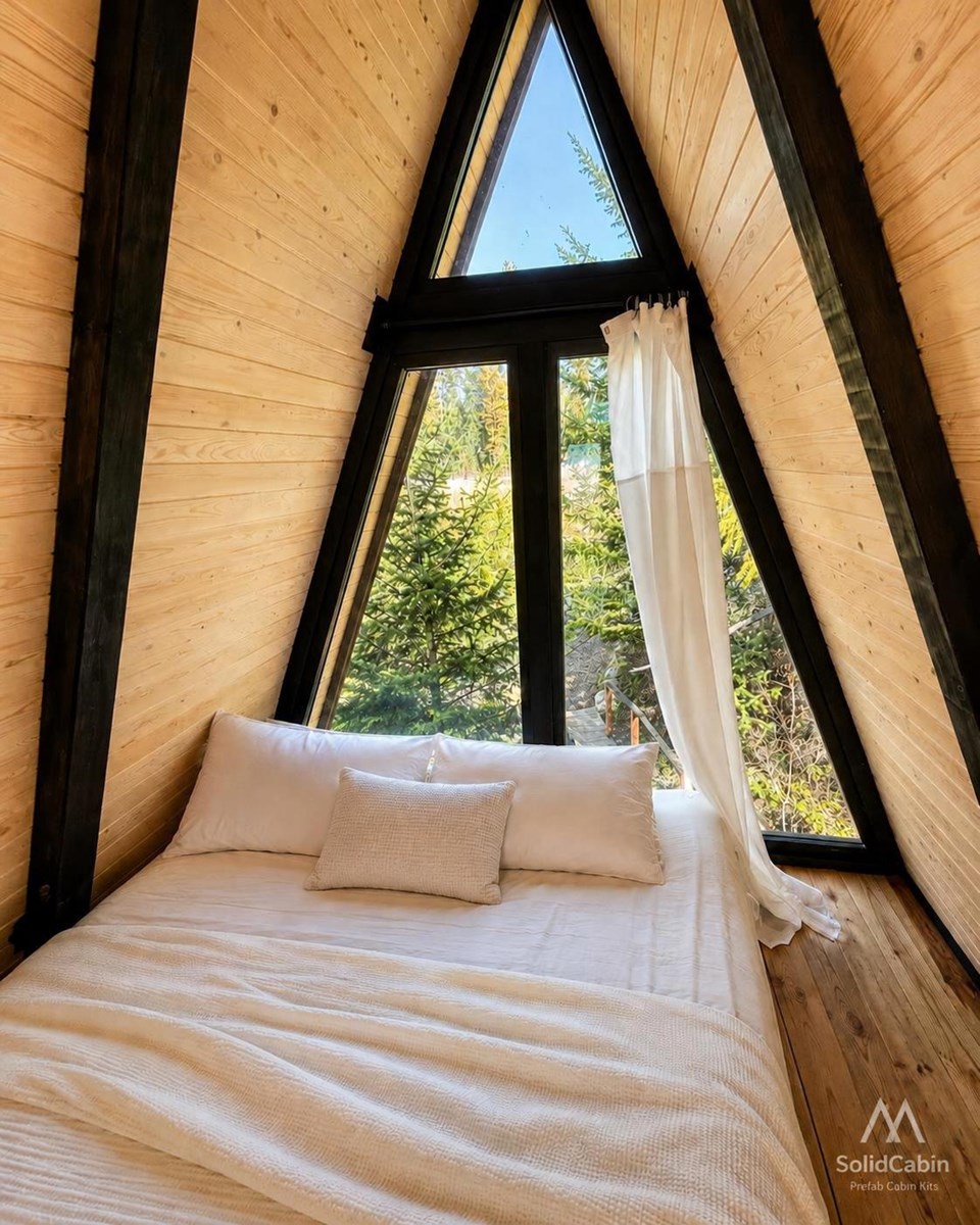 Loft bedroom with timber lining and a triangular window.