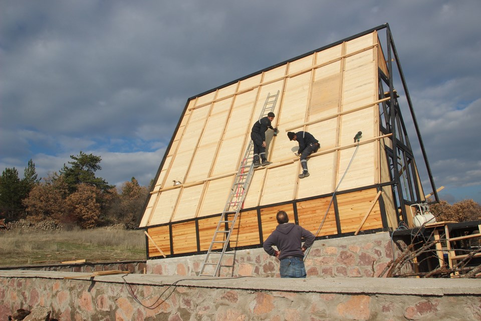 Crew installing insulated roof panels on the A-frame. Earlier Stella 70 application; project finishes and amenities vary.