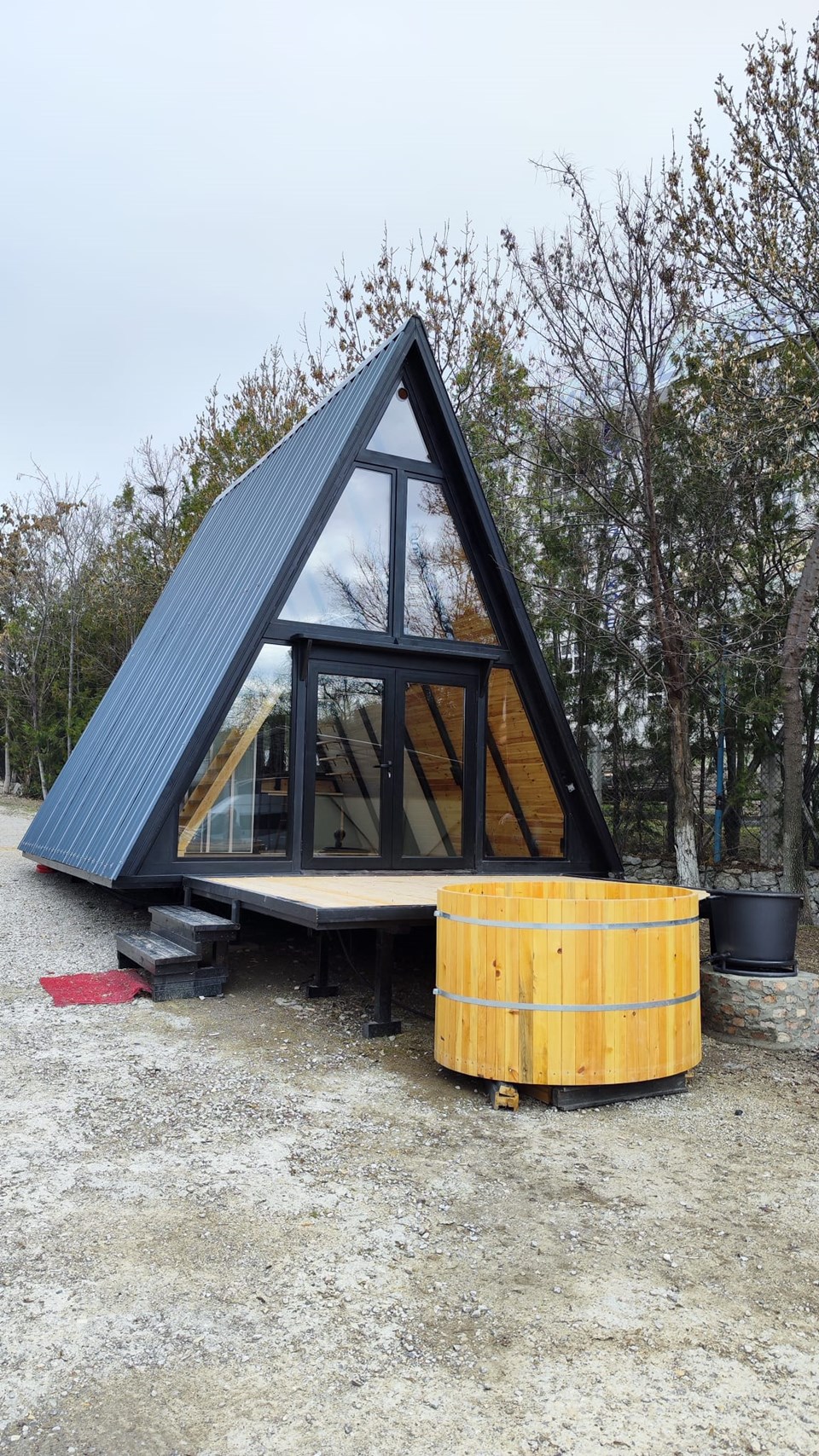 Completed Stella 53 A-frame cabin with a glazed front, timber deck and outdoor hot tub.