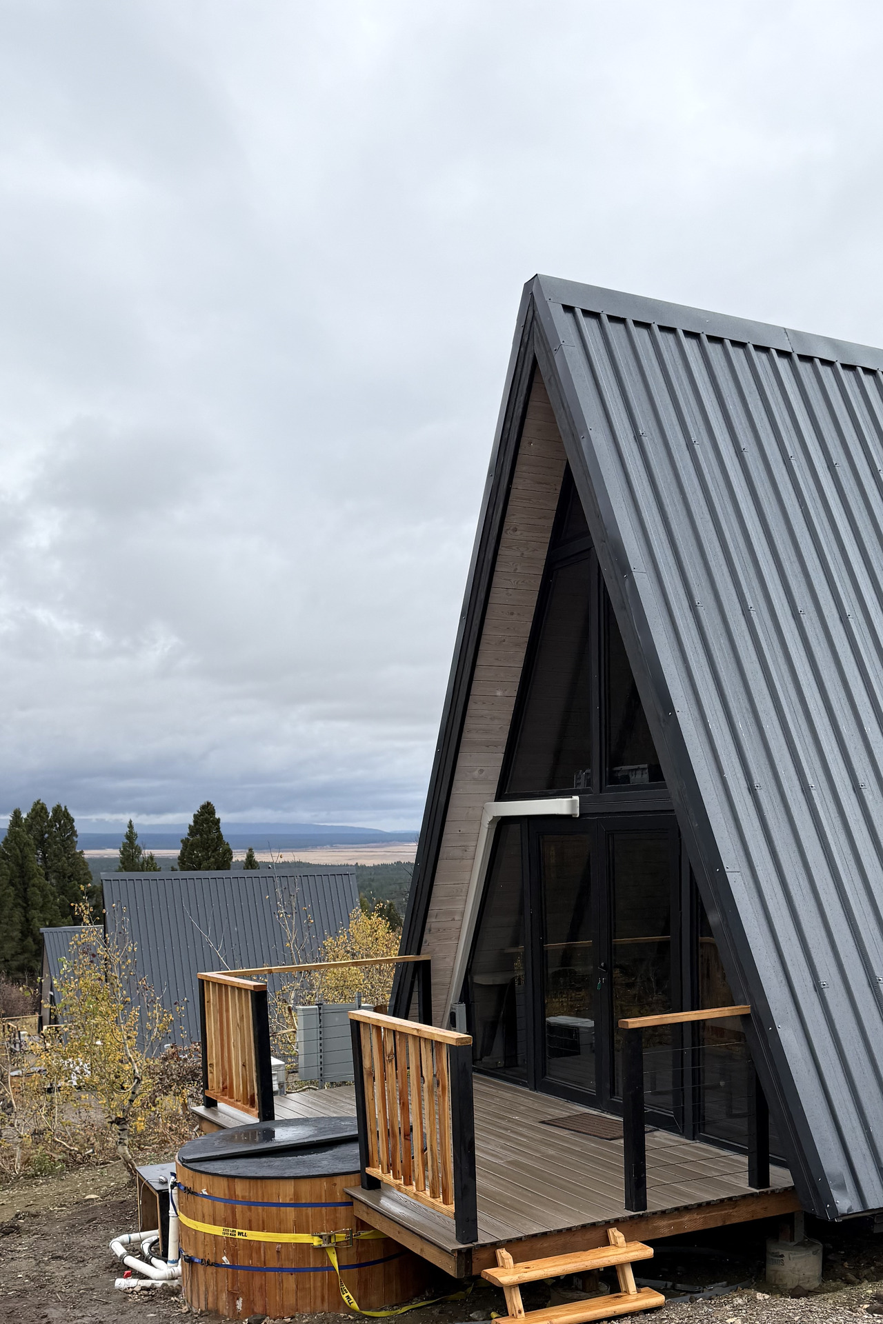 Rear deck and round hot tub at a completed Stella 53 A-frame cabin in Island Park, Idaho.