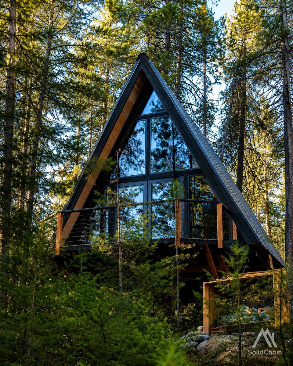 Completed glazed facade and dark roof in a natural setting.