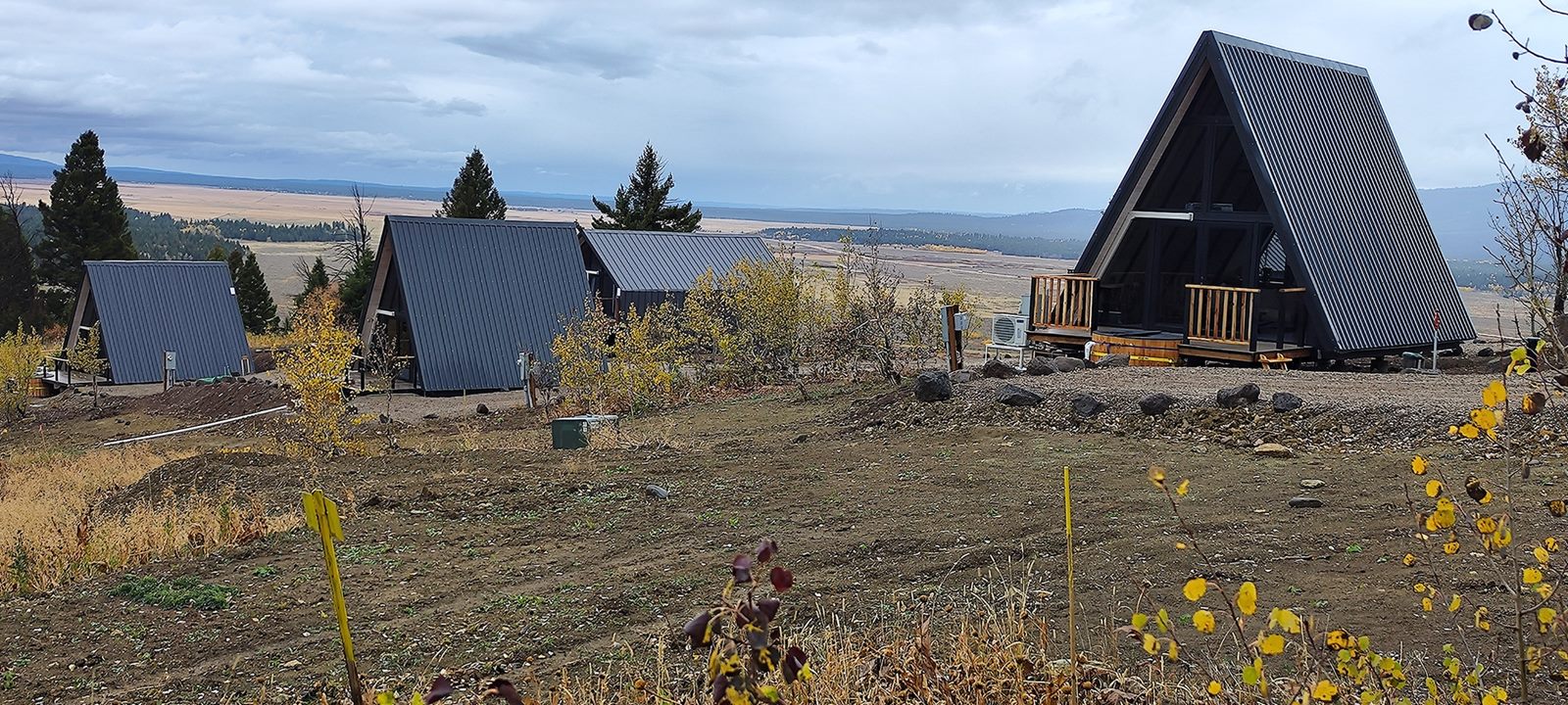 Wide landscape view of several A-frame cabins across the Island Park, ID development site.