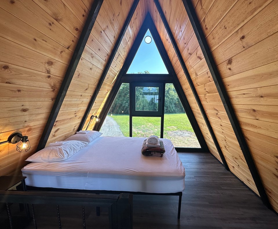 Stella 70 loft sleeping area beneath the timber-lined A-frame roof. Earlier West Virginia configuration.